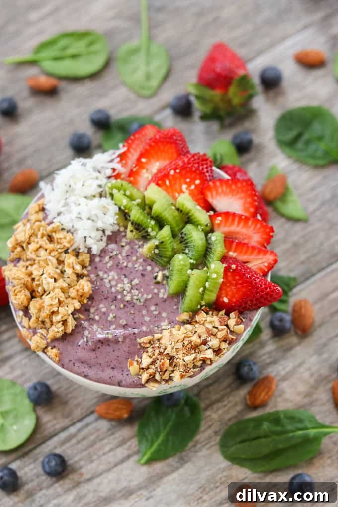 Blueberry Banana Smoothie Bowl with fruit, coconut and granola Close-up of a Blueberry Banana Smoothie Bowl adorned with fresh fruit, shredded coconut, and crunchy granola, showcasing its vibrant texture and inviting appeal.