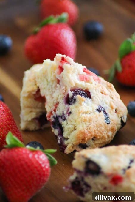 Homemade Mixed Berry Scones with Fair Trade Berries Mixed Berry Scones made with fresh strawberries and blueberries on a rustic wooden tray, surrounded by loose fresh berries.