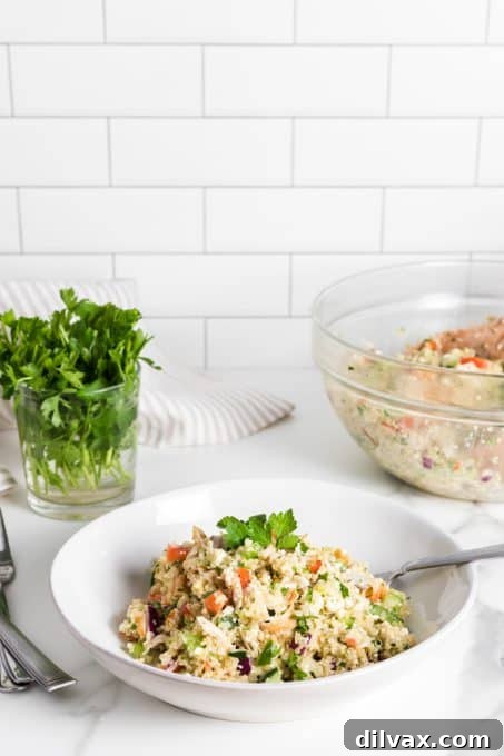 A close-up of Greek Quinoa Chicken Salad showing feta, chicken, and fresh vegetables mixed with a lemon vinaigrette.