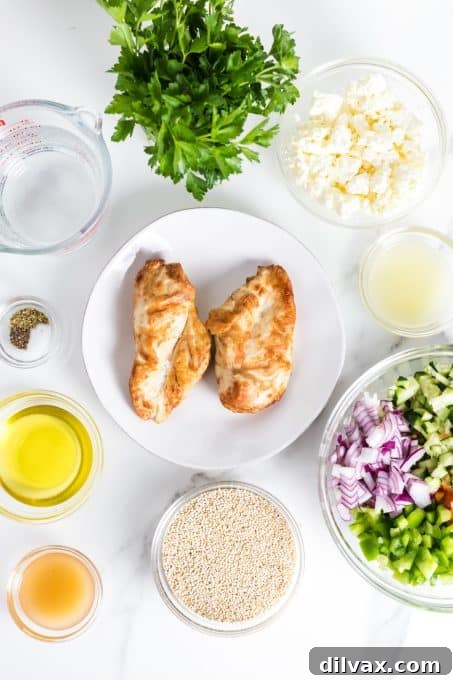 A flat lay of fresh ingredients including bell peppers, cucumber, feta cheese, and herbs, ready for a Greek Chicken Salad.