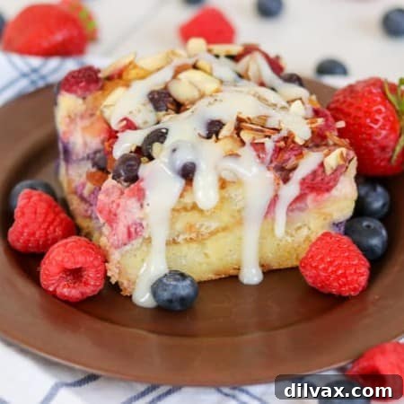Almond Berry French Toast Casserole drizzled with Barefeet in the Kitchen's Waffle Sauce, served for breakfast.