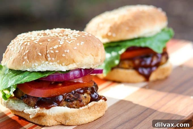 Two Cheesy Spiced Pork Burgers served on buns with fresh toppings like lettuce, tomato, and onion.