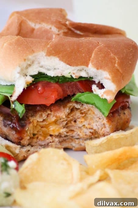 A Cheesy Spiced Pork Burger with a bite taken out of it, showing the juicy interior.