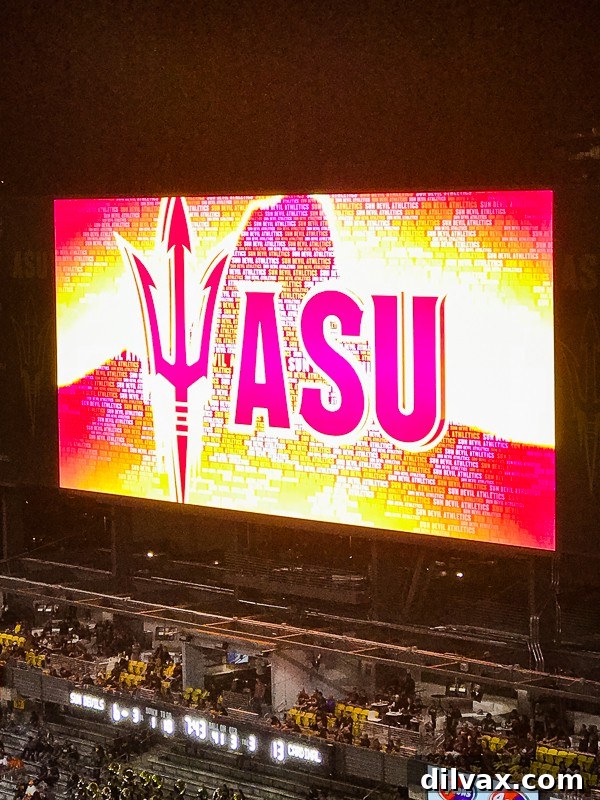ASU Sun Devil Stadium jumbotron displaying game information and vibrant sponsor messages during a football game.