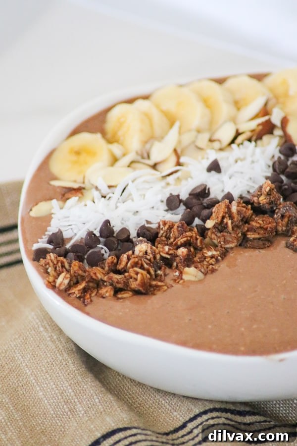 A vibrant and nutritious Banana Mocha Smoothie Bowl topped with various fresh fruits and healthy garnishes.