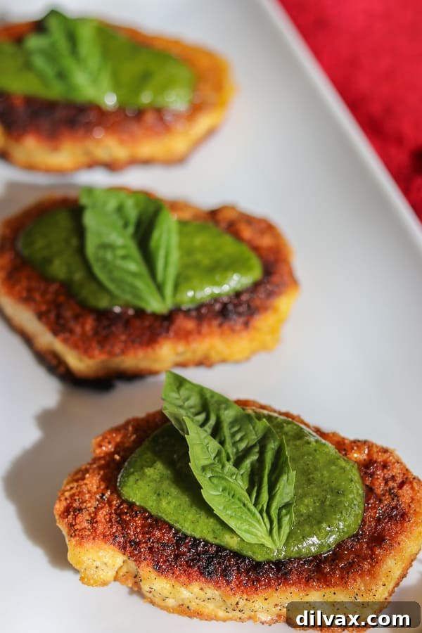 Three golden-brown Parmesan Pork Chops arranged neatly, showcasing their crispy Parmesan crust.