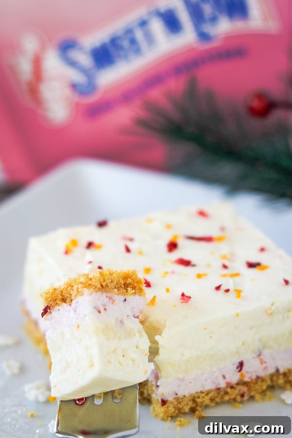 Close up of a Cranberry Orange Dream Bar with a bite taken out, showing the creamy layers.