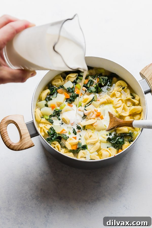 Adding cream to One Pot Bacon and Tortellini Zuppa Toscana. Pouring heavy cream into the simmering Zuppa Toscana, creating a rich and creamy texture.
