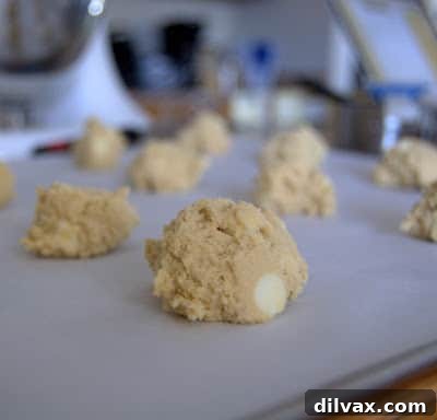 A wire rack filled with golden-brown, freshly baked white chocolate choco chip cookies, cooling after coming out of the oven.