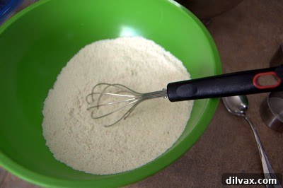 Mixing bowl with a whisk, showing the dry ingredients (oatmeal, flour, baking soda, salt) being combined for cookie dough.