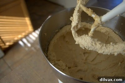 A stand mixer with a paddle attachment creaming butter and sugar until fluffy and pale, a crucial step for soft cookies.