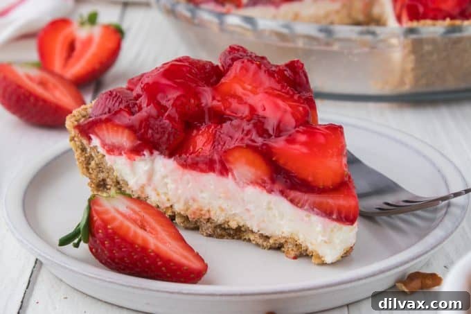A slice of Strawberry Pretzel Pie with a perfect balance of a golden pretzel crust, white cheesecake filling, and red strawberry topping.