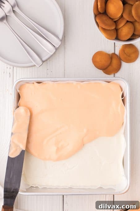 Orange Cloud Nine Bars 7 Spreading the orange cream topping over the cheesecake layer in a pan