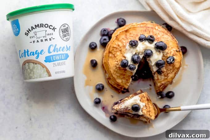 Lemon Blueberry Cottage Cheese Pancakes with Shamrock Farms A stack of golden Lemon Blueberry Cottage Cheese Pancakes with fresh blueberries and lemon slices on top, showcasing Shamrock Farms Low-fat Cottage Cheese as a key ingredient.