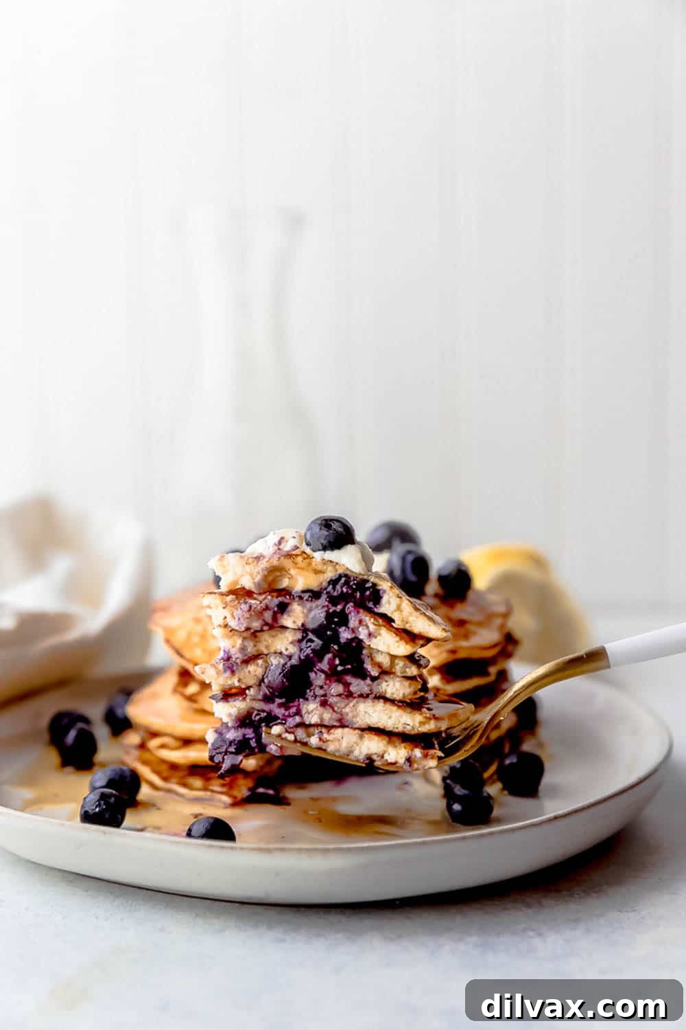 Stack of Lemon Blueberry Cottage Cheese Pancakes A high stack of golden Lemon Blueberry Cottage Cheese Pancakes, topped generously with fresh blueberries and a light dusting of powdered sugar, enticing and ready to serve.