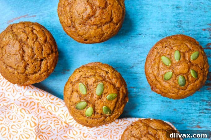 Close-up of a stack of moist Dairy-Free Pumpkin Muffins next to an orange napkin, perfect for fall.