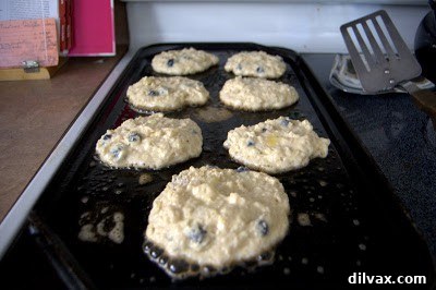 Pancakes cooking on a griddle, browning on the bottom