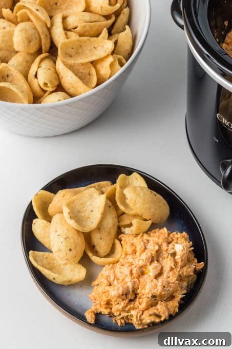 Mixing Slow Cooker Chicken Dip with Buffalo sauce in a bowl.