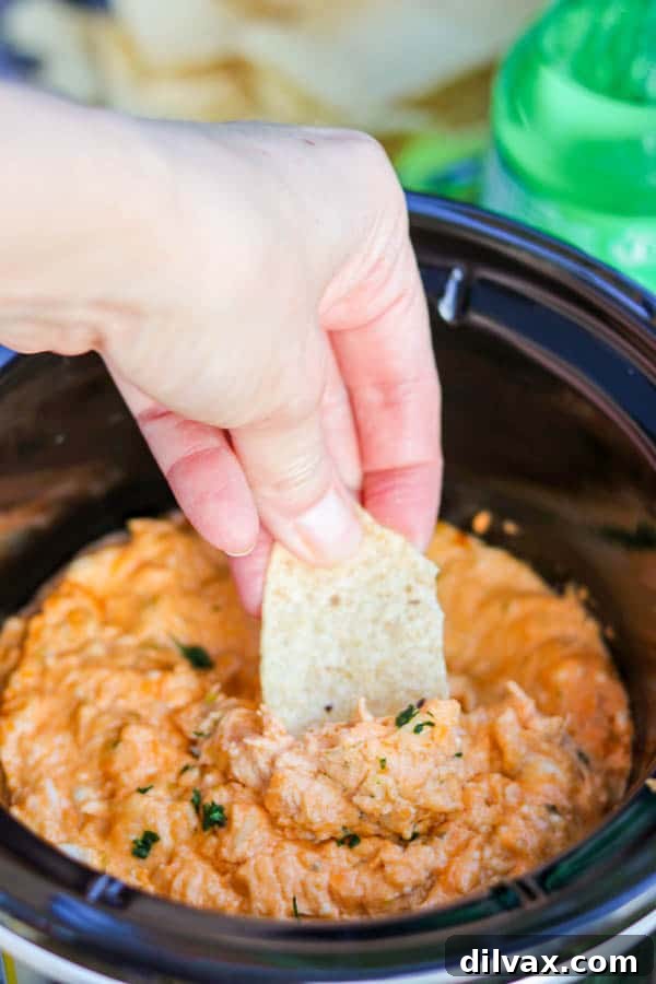 A tortilla chip being dipped into Slow Cooker Buffalo Chicken Dip.