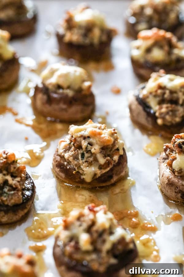 A baking sheet of Cheesy Sausage Stuffed Mushrooms fresh from the oven. A baking sheet of baked Cheesy Sausage Stuffed Mushrooms.