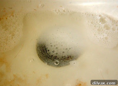 A close-up of a dirty bathroom sink basin with visible stains, highlighting the need for cleaning and drain maintenance.