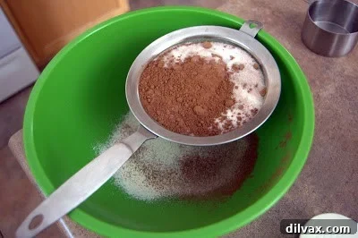 Sifting dry ingredients: flour, sugar, cocoa powder, baking powder, and salt into a bowl for Chocolate Cherry Crinkles.
