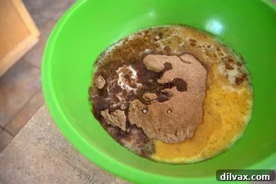 Adding beaten eggs and melted butter to the sifted dry ingredients for Chocolate Cherry Crinkles dough.