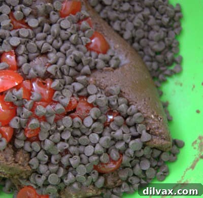 Mixing mini chocolate chips, quartered maraschino cherries, and cherry juice into the Chocolate Cherry Crinkles dough.