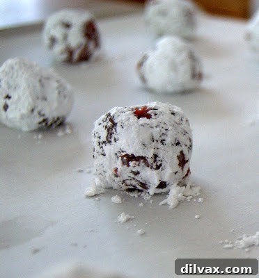 Baked Chocolate Cherry Crinkles cooling on a baking sheet, showing their unique crackled, powdered sugar coating.