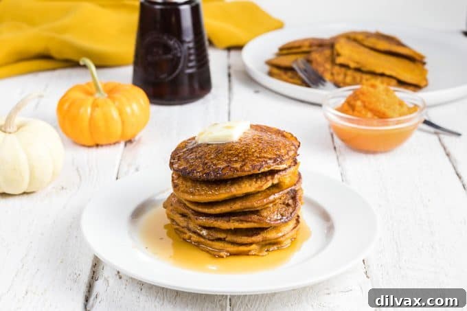 Hearty Pumpkin Wheat Stack 2 A tall stack of fluffy pumpkin pancakes with butter and maple syrup drizzled on top, ready for a delicious breakfast.