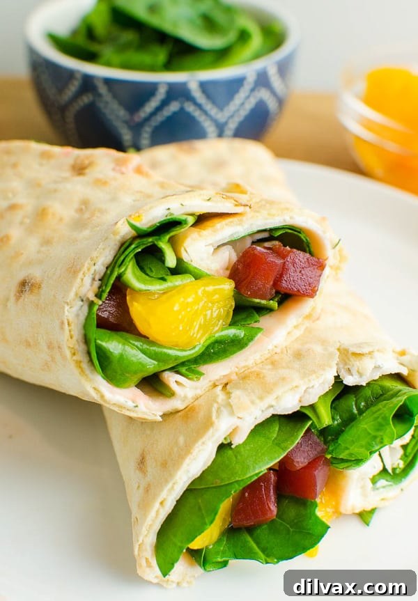 A vibrant Beet, Turkey and Cheese Wrap, showcasing its colorful fillings, sliced in half and ready to eat.
