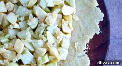 Finely chopped crystallized ginger evenly sprinkled over the prepared apple filling on the galette, enhancing flavor.
