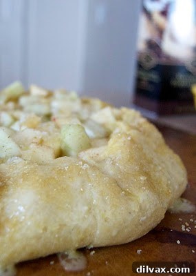 Assembled galette with folded edges, brushed with egg wash, sprinkled with turbinado sugar and freshly grated nutmeg, ready for baking.