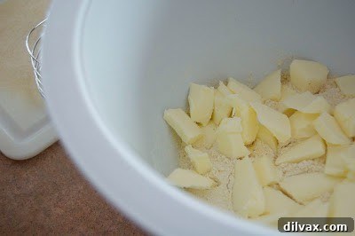 Small, cold butter pieces carefully added to the dry ingredient mixture for the galette crust, awaiting blending.