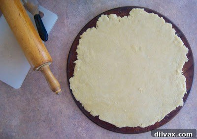 Galette dough expertly rolled out into an approximate 14-inch circle on a parchment-lined baking sheet, forming the base.