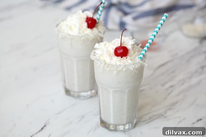A cold, refreshing taste of the tropics in each sip of these Pina Colada Milkshakes, garnished with pineapple.