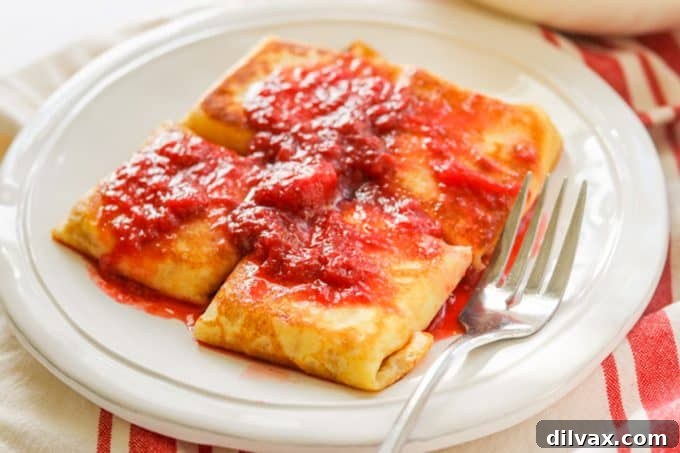 Unlock the Secrets to Perfect Cheese Blintzes 2 A plate of blintzes covered in strawberry sauce.