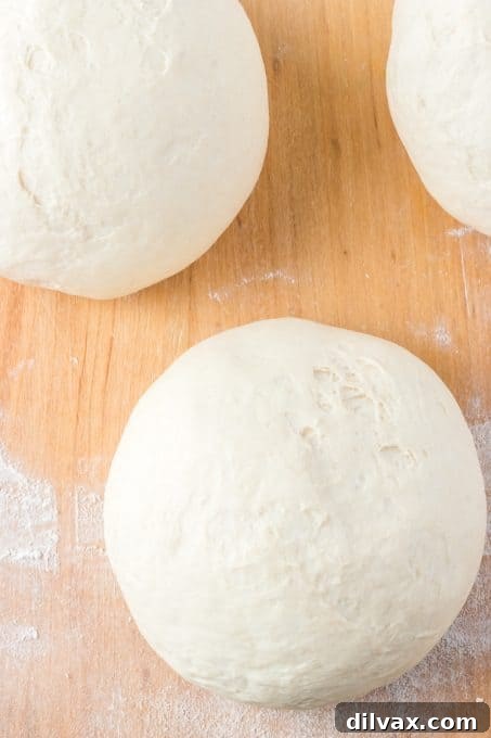Pizzeria-Quality Pizza Dough At Home 11 Balls of pizza dough made at home. Perfectly formed pizza dough balls on a floured surface.
