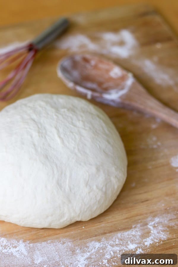 A wooden spoon and whisk are two of the utensils used to make pizza dough. The easiest and best recipe when you need dough for your pizza. A wooden spoon and whisk in a mixing bowl with dough ingredients.