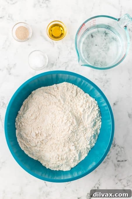 Pizzeria-Quality Pizza Dough At Home 5 Ingredients for Homemade Pizza Dough. Various ingredients like flour, yeast, salt, water, and olive oil laid out.