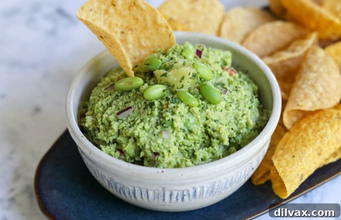 A chip in guacamole topped with edamame.