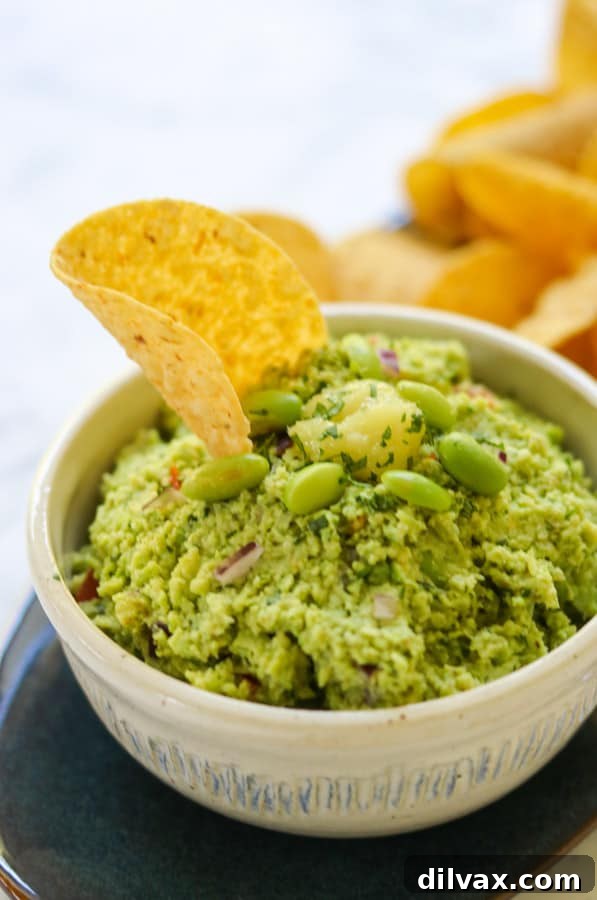 A tortilla chip stuck in edamame guacamole.