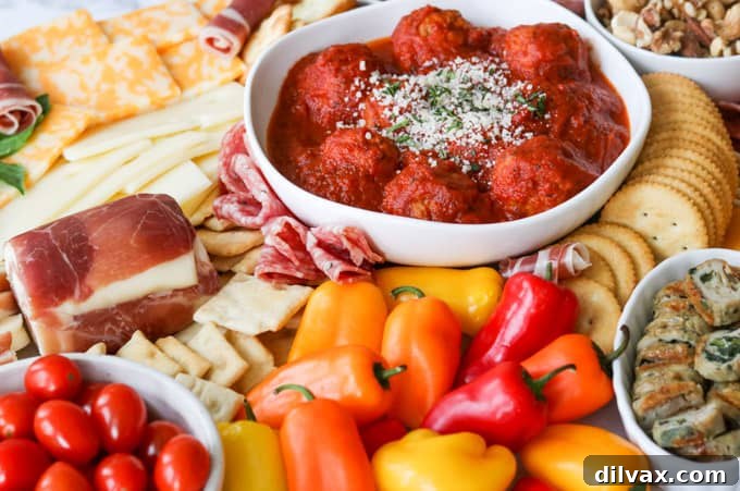 The Art of Building a Charcuterie Board 2 Meatballs, small peppers, tomatoes on a meat and cheese board / charcuterie.
