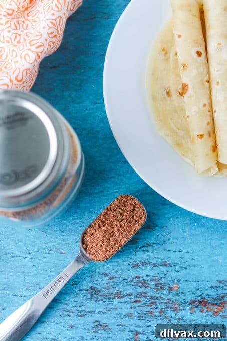 DIY Taco Spice Blend 7 A rustic wooden spoon rests atop a pile of richly colored homemade seasoning for tacos and other Mexican dishes, inviting a culinary adventure.