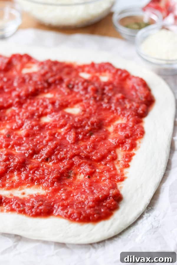 Smooth pizza sauce spread generously over a canvas of fresh pizza dough.