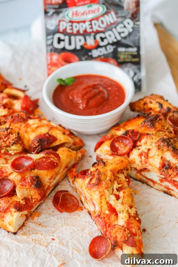 Golden-brown slices of Double Pepperoni Bread Twist, artfully arranged beside a bowl of vibrant marinara sauce, ready for dipping.
