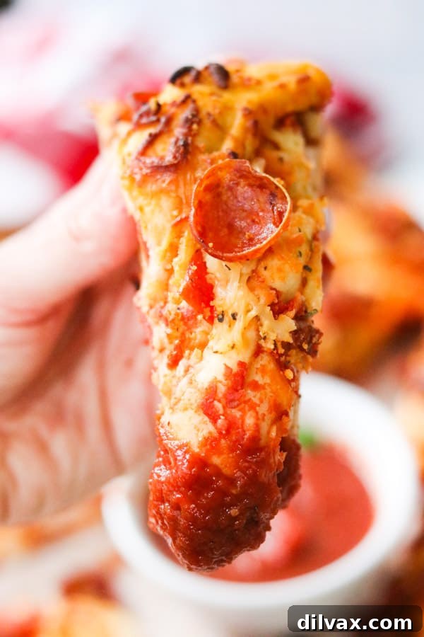 A mouthwatering slice of golden-brown Pepperoni Bread Twist, generously dipped in rich, red marinara sauce.
