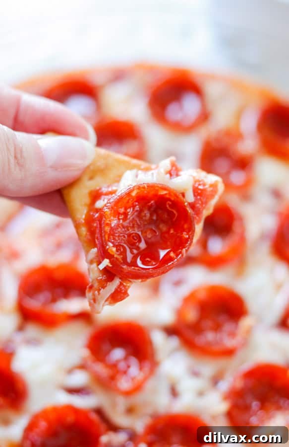 Pepperoni Pizza dip on a pita chip. A pita chip loaded with hot pepperoni pizza dip.