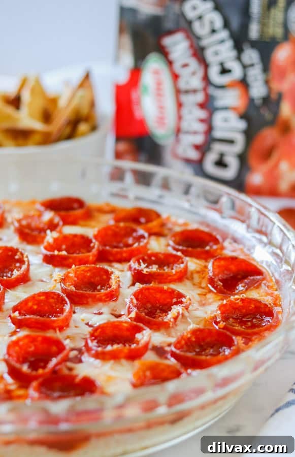 Cooked pepperoni in a hot pizza dip. Pie plate full of a cheesy dip appetizer, topped with perfectly cooked pepperoni cups.