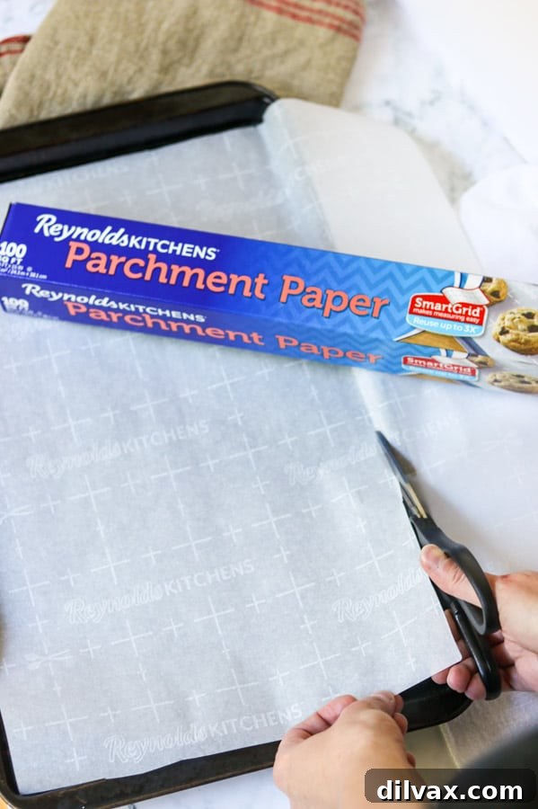 Cutting parchment paper for baking Cutting Reynolds Kitchens® Parchment Paper with SmartGrid® to fit a cookie sheet, highlighting the grid pattern.